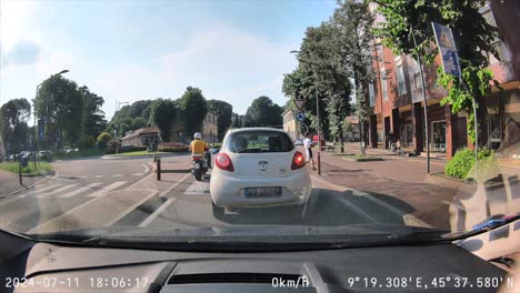 A-car-drives-through-a-traffic-circle-through-town,-dash-cam-recording