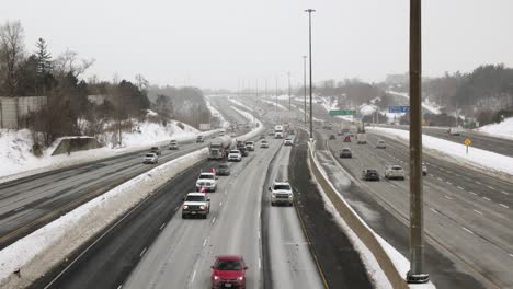 LKW-Konvoi-Mit-Kanadischen-Flaggen,-Die-Schilder-Schwenkten,-Demonstrationsfahrt-Auf-Der-Autobahn-Bei-Winterschnee-In-Einem-Städtischen-Umfeld-Aus-Protest