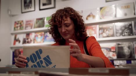 Thrilled-Curly-Woman-Browsing-Through-Vinyl-Records-In-Music-Store