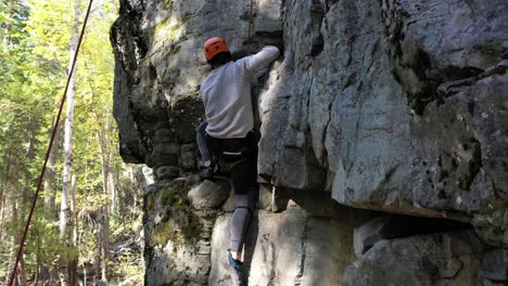 Escalador-De-Roca-En-Un-Acantilado-Natural-En-Whitefish,-Montana,-EE.-UU.---Toma-Inclinada-Hacia-Arriba