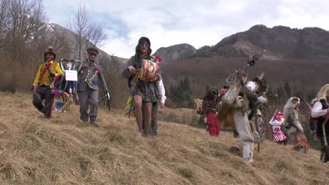 Carnival-characters-with-masks-walk-down-grassy-slope-on-festive-Saturday