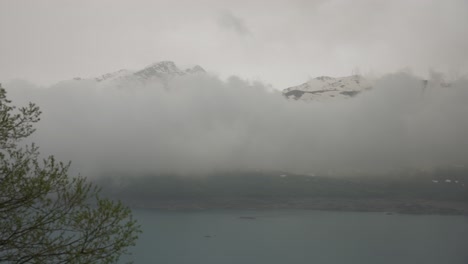 Low-clouds-cover-snowy-mountains-on-cloudy-day,-Mont-Cenis-Lake,-France