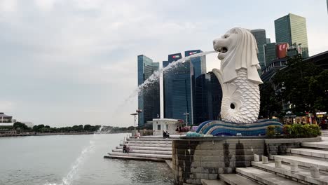 Iconic-Singapore-mascot,-mythical-creature-merlion-fountain-at-downtown-metropolitan-area-with-business-and-financial-buildings-in-the-background