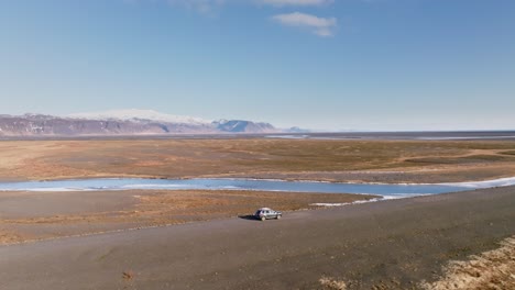 Car-drives-on-off-road-in-scenic-Iceland-mountain-and-desert-panorama,-aerial