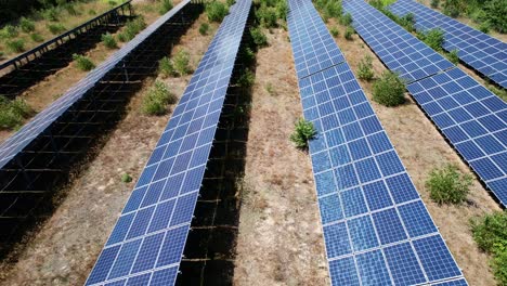 Clip-De-Dron-Moviéndose-Hacia-Atrás-Sobre-El-Campo-Y-Una-Granja-Solar-Con-Energía-Fotovoltaica