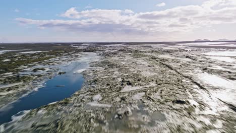 Vuelo-Aéreo-Rápido-Y-Bajo-Sobre-Un-Paisaje-De-Tundra-Derretida-Con-Nieve-Y-Ríos