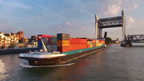 Cargo-Ship-Passing-Through-Lift-Bridge-at-Sunset,-Infrastructure-for-Water-Transport