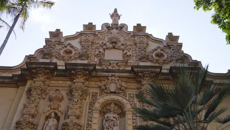 The-intricate-baroque-facade-of-the-Casa-del-Prado-Theater-in-Balboa-Park-is-a-masterpiece-of-Spanish-colonial-revival-architecture,-adorned-with-detailed-carvings-and-surrounded-by-lush-greenery