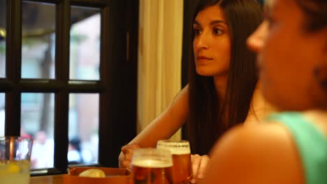 Two-women-listening-to-another-one-while-having-some-drinks,-soft-focus