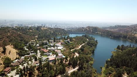 Aerial-establishing-shot-of-luxury-neighborhood-with-mansions-and-Hollywood-reservoir-during-sunny-day