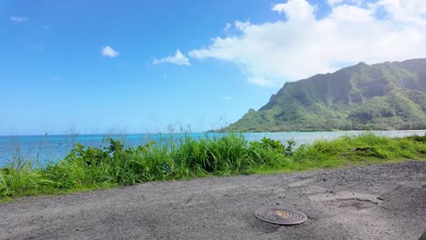 car-driving-along-the-picturesque-coastal-road-above-dramatic-rocky-shore-towards-beautiful-volcanic-mountains-in-Oahu-hawaii-honolulu-island