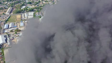 Aerial-into-black-plumes-of-smoke-rising-from-industrial-warehouse-fire