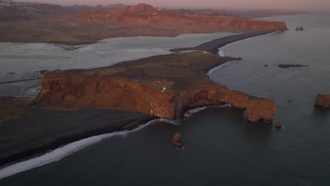 Vista-Panorámica-Estática-Del-Arco-De-Roca-Dyrhólaey-En-Islandia-Con-Luz-Naranja-Del-Amanecer