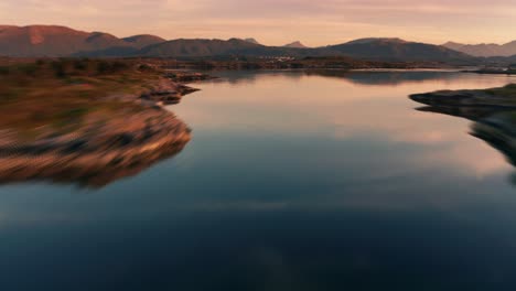 Flight-over-the-mirrorlike-ocean,-rocky-archipelago,-and-scattered-fishing-villages