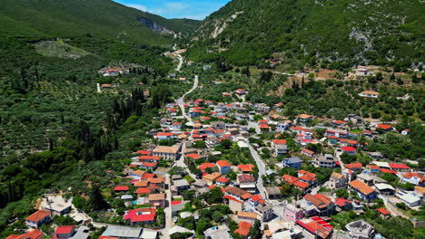 Greek-village-houses-from-above-surrounded-by-green-valley-nature,-aerial