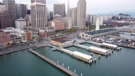 Aerial-drone-footage-captures-the-the-Ferry-Building-in-San-Francisco,-where-urban-greenery-and-historic-architecture-blend-seamlessly-along-the-vibrant-Embarcadero