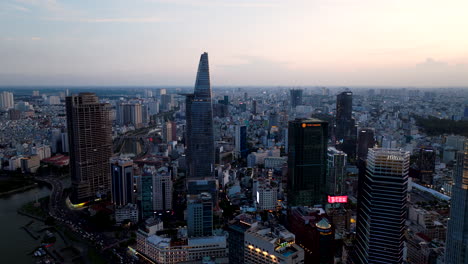 Luftanflug,-Während-Die-Skyline-Von-Saigon-Mit-Blick-Auf-Das-Flussufer-In-Der-Dämmerung-Aufleuchtet