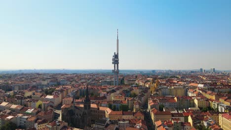 Drone-footage-of-Prague's-Žižkov-Television-Tower-rising-above-the-cityscape,-providing-a-striking-contrast-to-the-surrounding-historic-buildings-and-urban-environment