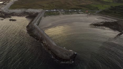 Aerial-view-of-Spiddal-beach-and-pier-bathed-in-stunning-sunset-light