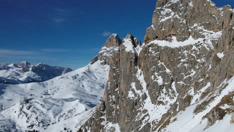 Drohnenüberflug-Erfasst-Die-Majestätischen-Schneebedeckten-Gipfel-Der-Dolomiten-Und-Enthüllt-Eine-Atemberaubende-Alpenlandschaft-Unter-Einem-Klaren-Blauen-Himmel