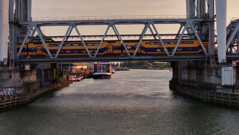 Gelber-NS-Zug-Fährt-über-Eine-Niederländische-Brücke,-Das-Beliebteste-öffentliche-Verkehrsmittel-In-Den-Niederlanden-Und-Das-Beste-Eisenbahnnetz-In-Europa