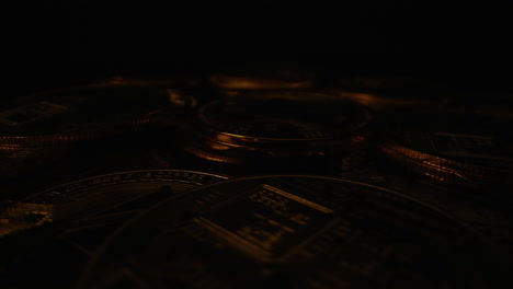 Gold-Coins-on-a-Rotating-Platform,-Illuminated-by-a-Flickering-Light-Against-a-Dark-Background---Close-Up