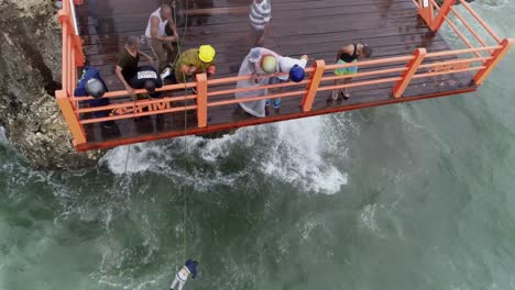 Rescuers-on-a-shoreline-platform-pulling-the-rope-attached-to-the-body-recovered-from-the-Caribbean-Sea,-with-people-watching-from-the-same-platform