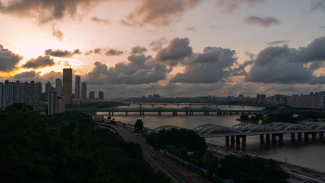 Hermoso-Atardecer-Dramático-Sobre-El-Río-Han-Con-Vistas-A-Numerosos-Puentes,-63-Edificios-Y-Lapso-De-Tiempo-Del-Tráfico-Vehicular-En-La-Autopista-Olympic,-En-El-Distrito-De-Yeouido-En-La-Ciudad-De-Seúl,-Corea-Del-Sur---Panorama-Estático