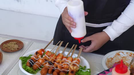 Woman-Hand-Adding-Mayonnaise-and-Mustard-Sauce-Onto-Suki-Satay