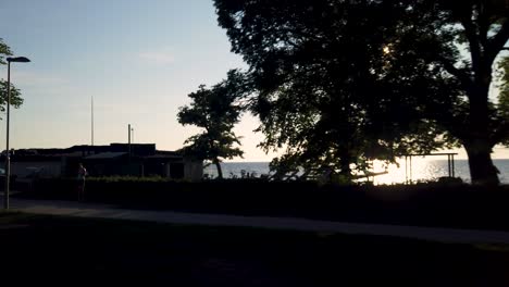 People-on-seaside-promenade-and-outdoor-gym-by-coast-of-Gotland,-Sweden,-at-sunset