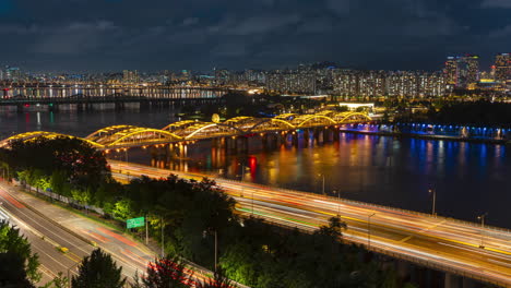 Time-lapse-De-La-Noche-En-Seúl,-Movimiento-De-Automóviles-En-La-Autopista-Olímpica-Y-El-Puente-Hangang-Sobre-El-Río-Han,-Apartamentos-Del-Distrito-De-Yongsan---Inclinación-Lenta-Hacia-Arriba