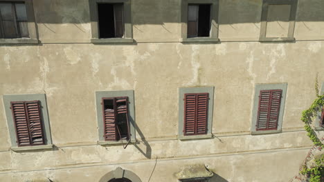 Old-Italian-villa-with-cracked-walls,-broken-windows,-and-a-weathered-facade,-aerial-view