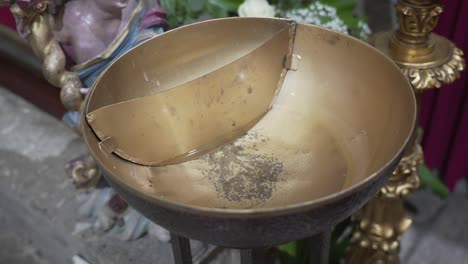 Close-up-of-an-aged-brass-offering-bowl-in-a-religious-setting,-highlighting-the-patina-and-historic-significance