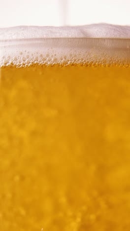 Close-up-of-beer-pouring-into-glass.-Lager-foamy-beer-with-big-bubbles-rising-upwards.-Hop-taste.-Concept-of-beer-drink,-brewery,-taste,-bar,-degustation,-festival,-drink-texture.-Vertical-layout