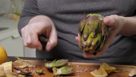 Woman-cleaning-artichokes-with-knife.-Cooking-process-at-the-kitchen.-Closeup