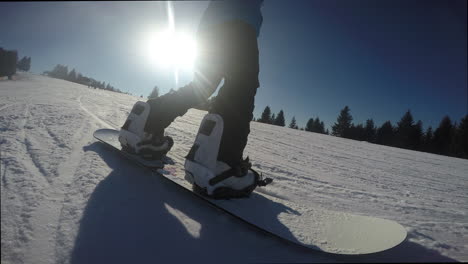 A-closeup-of-a-snowboarder-riding-on-a-snowy-hill-against-sun-rays-in-a-blue-sky