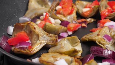 Cooking-artichoks-and-vegetables-on-frying-pan.-Closeup