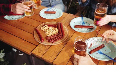 Young-people-meeting-at-pub,-drinking-lager-foamy-beer-and-eating-delicious-snack-with-pretzels-and-sausages.-Concept-of-oktoberfest,-traditional-taste,-friendship,-leisure-time,-enjoyment