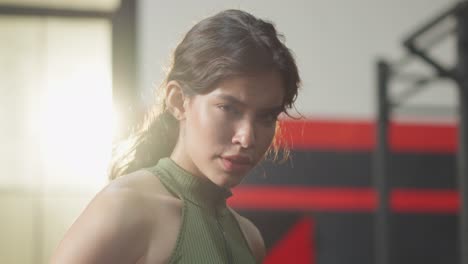 Portrait-of-Latino-sport-girl-in-sportwear-exercising-in-fitness-club.-Attractive-athlete-young-female-stand-with-confidence-after-finished-workout-with-machines-and-equipment-in-gym-or-fitness-club