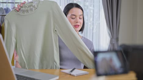 Chica-Joven-Atractiva-Asiática-Que-Vende-Productos-En-Línea-En-Vivo-Durante-La-Pandemia-De-COVID-19.-La-Mujer-De-Televenta-Muestra-La-Tela-Al-Cliente-Y-Le-Muestra-Los-Detalles.-Tecnología-De-Compra-Y-Adquisición-Remota