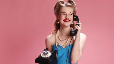 Beautiful-young-girl-with-blonde-hair-taking-on-phone-over-pink-studio-background.-Diversity-of-emotions.-Concept-of-retro-fashion,-beauty,-attraction,-50s,-60s.-Pin-up-style.-Vintage