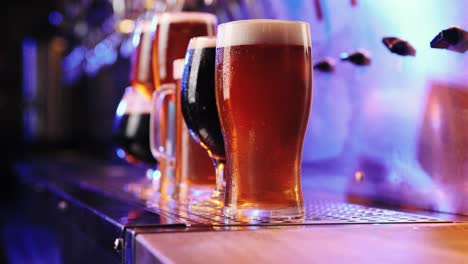 Close-up-image-of-beer-glasses-with-dark-and-lager-beer-in-neon.-Selective-focus.-Cool,-chill-drink.-Refreshment.-Bar,-pub-atmosphere.-Concept-of-alcohol-drink,-party,-taste,-relaxation.-