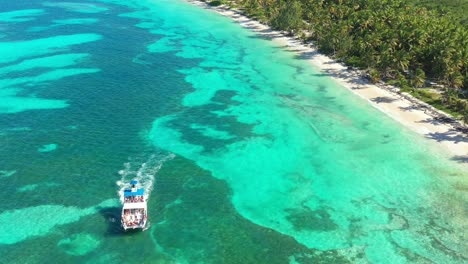 Bounty-and-pristine-tropical-shore-with-resorts,-palm-trees-and-caribbean-sea-with-floating-boats.-Travel-destinations.-Dominican-Republic.-Aerial-view