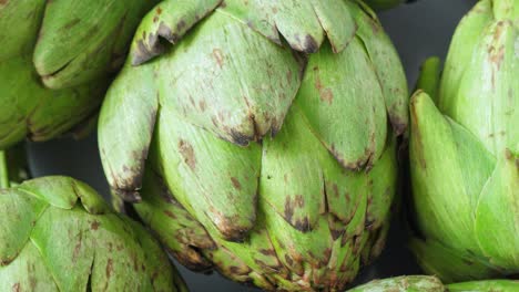 Whole-fresh-artichokes-on-plate,-rotate.-Closeup