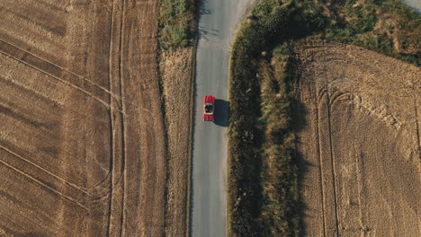 An-aerial-view-of-a-red-vintage-convertible-car-driving-through-agricultural-fields-in-Germany