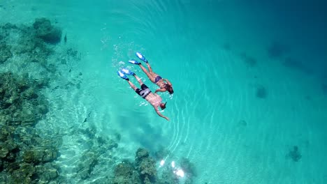 An-aerial-view-of-a-couple-holding-hands-and-swimming-in-the-sea-shot-in-4