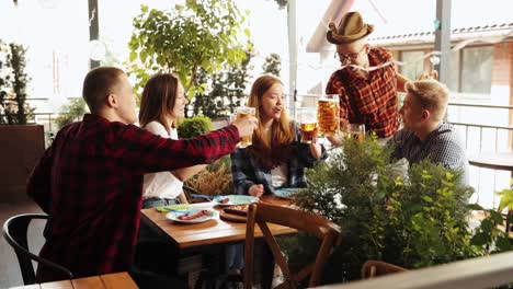 Beautiful,-positive-young-people,-friends-meeting-at-cafe,-pub,-drinking-beer,-having-good-time.-Festival.-Concept-of-oktoberfest,-traditional-taste,-friendship,-leisure-time-and-enjoyment