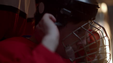 A-hockey-player-in-red-uniform-getting-ready-in-locker-room-with-a-serious-face