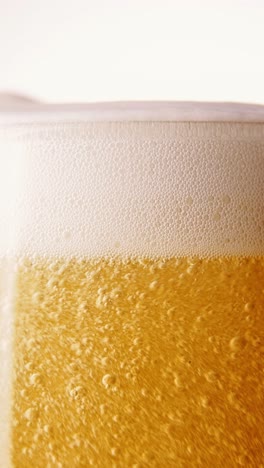 Frothy-drink.-Close-up-of-beer-pouring-into-glass.-Lager-foamy-beer-with-big-bubbles-rising-upwards.-Concept-of-beer-drink,-brewery,-taste,-bar,-degustation,-festival,-drink-texture.-Vertical-layout