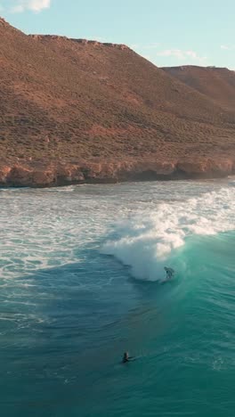 A-vertical-shot-of-a-young-man-surfing-on-the-big-waves-of-the-ocean